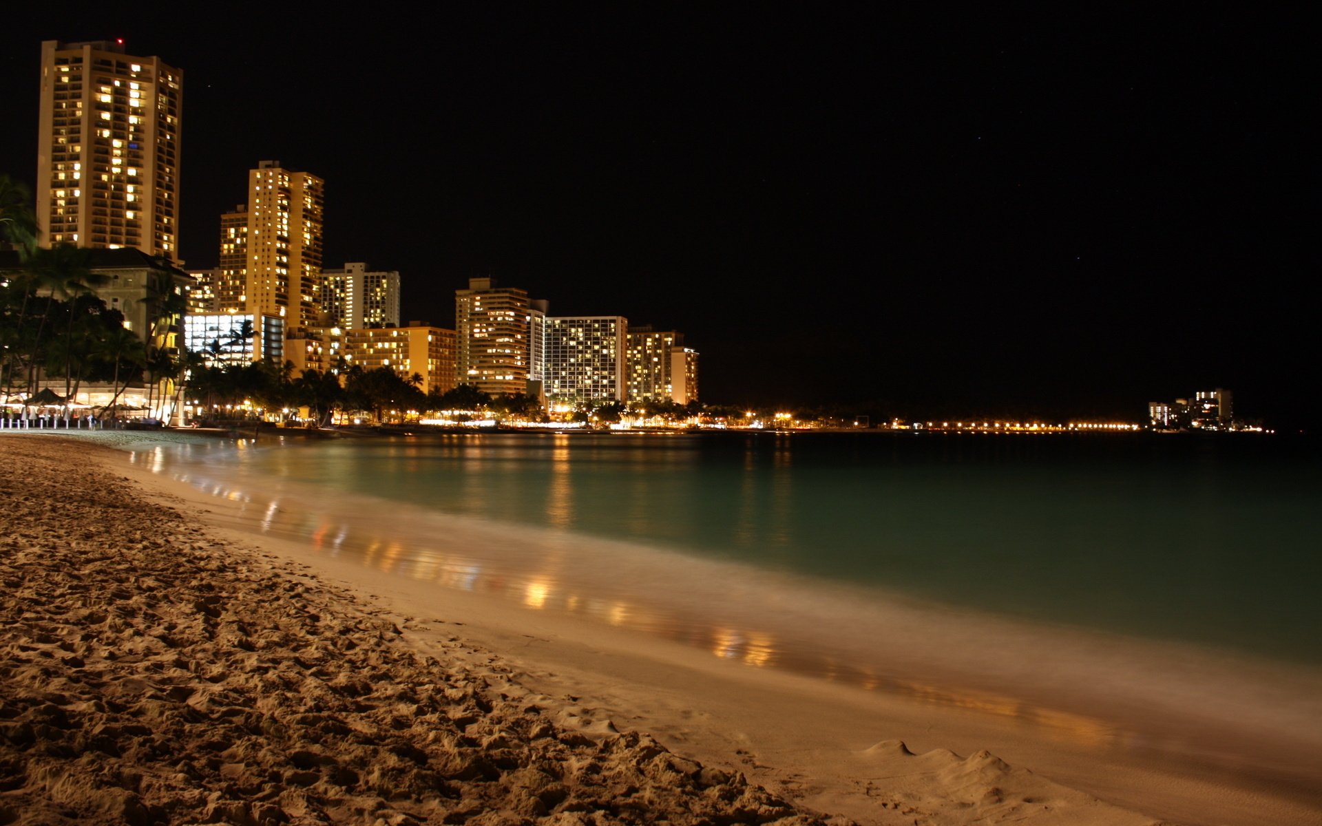 The beach near the city with illuminated skyscrapers
