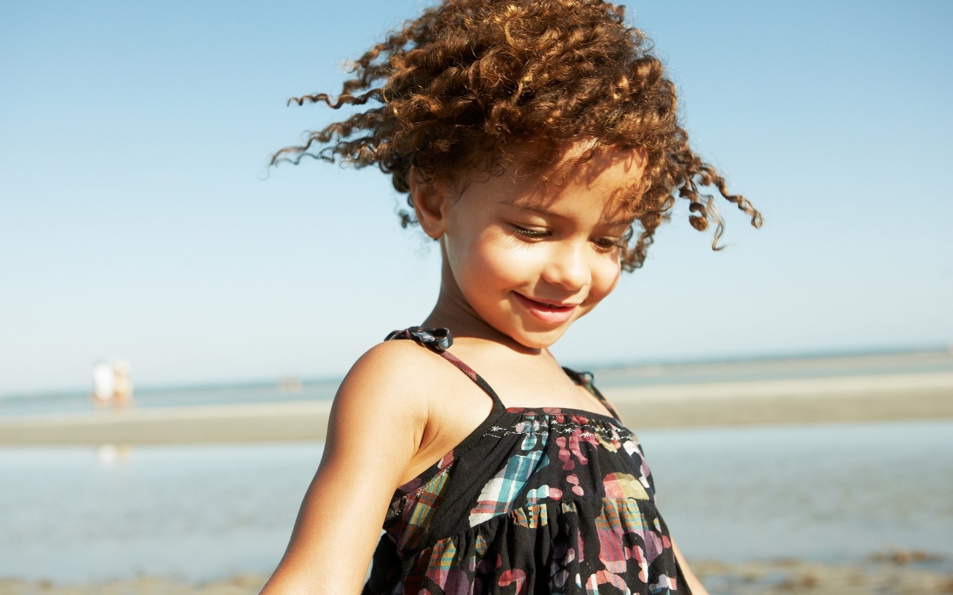 A girl with curls by the sea. The girl's smile