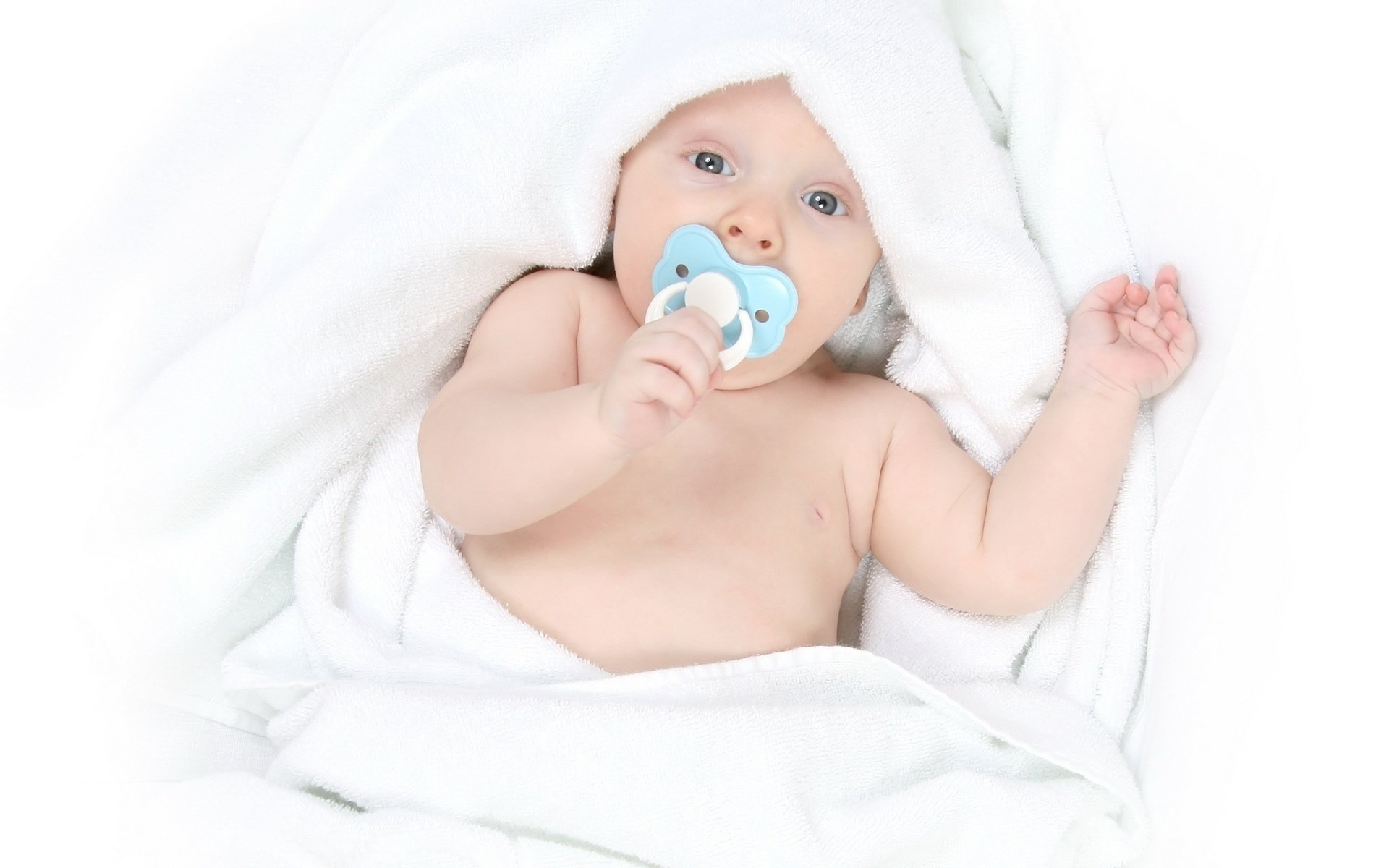 Baby with a pacifier in his mouth in a white blanket