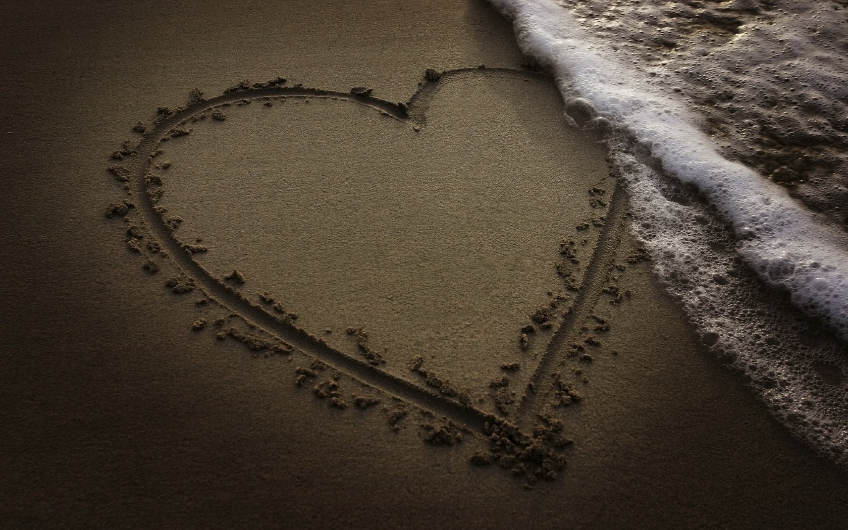 A heart painted on the sand near the sea