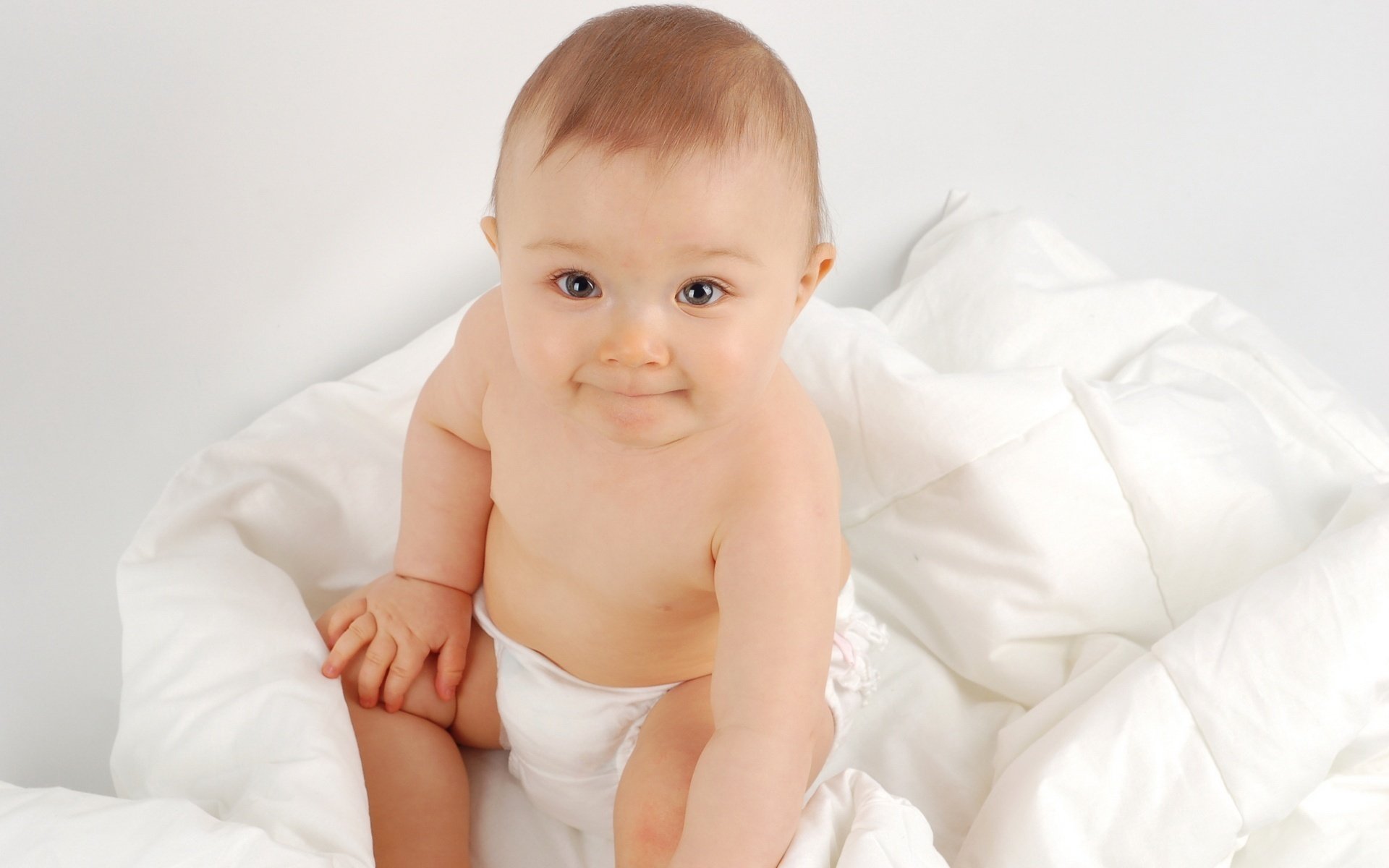 Cute baby on a white blanket in a diaper