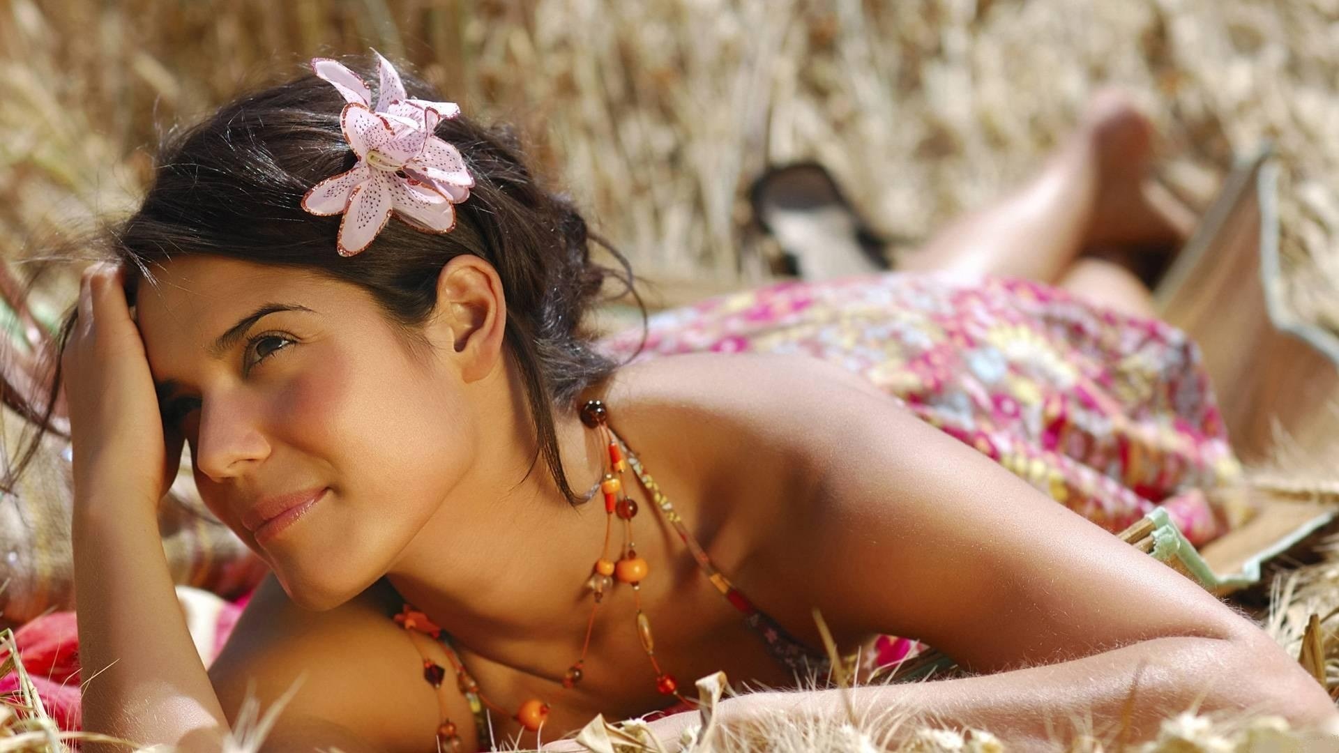 A beautiful girl with a flower in her hair lies and looks tempting. Hawaiian motifs