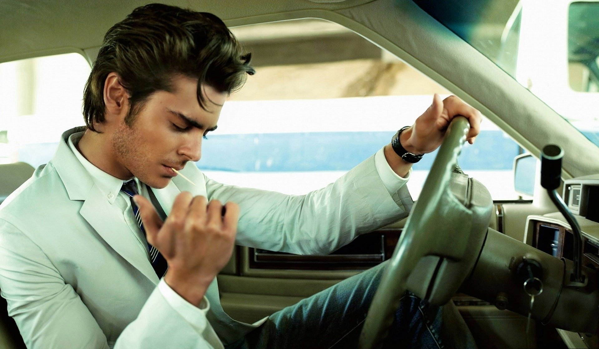 A handsome man in a shirt is sitting in a car