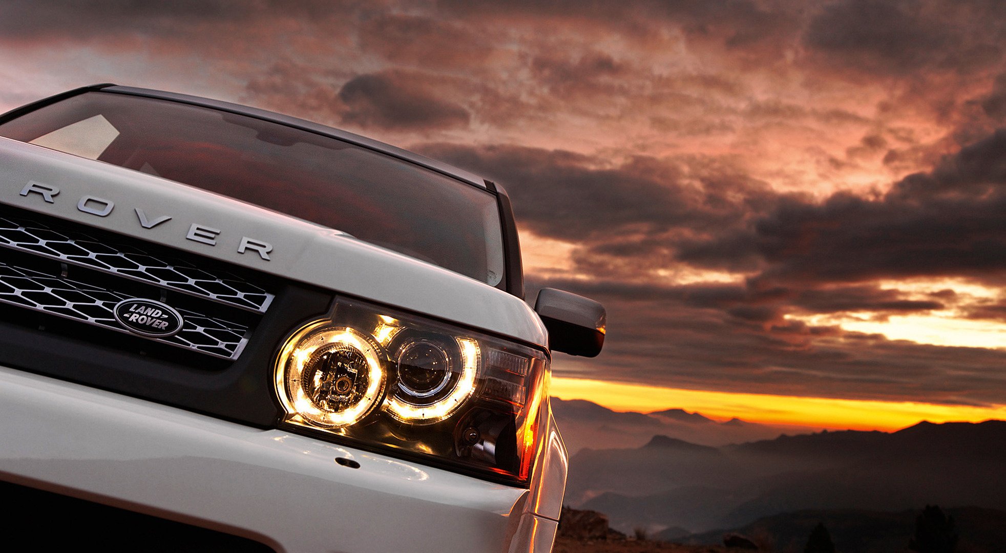 White car at sunset mountain. Range Rover with new headlights