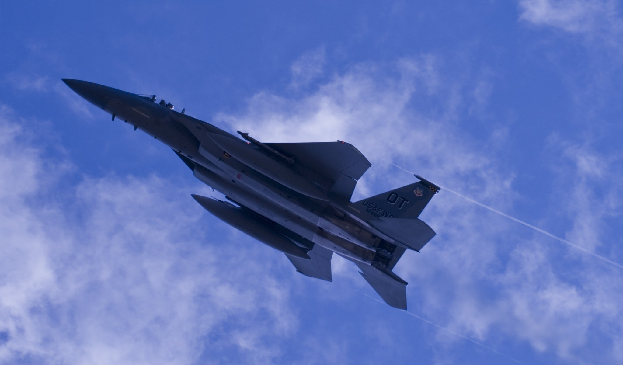 A military fighter is gaining altitude in a cloudy sky