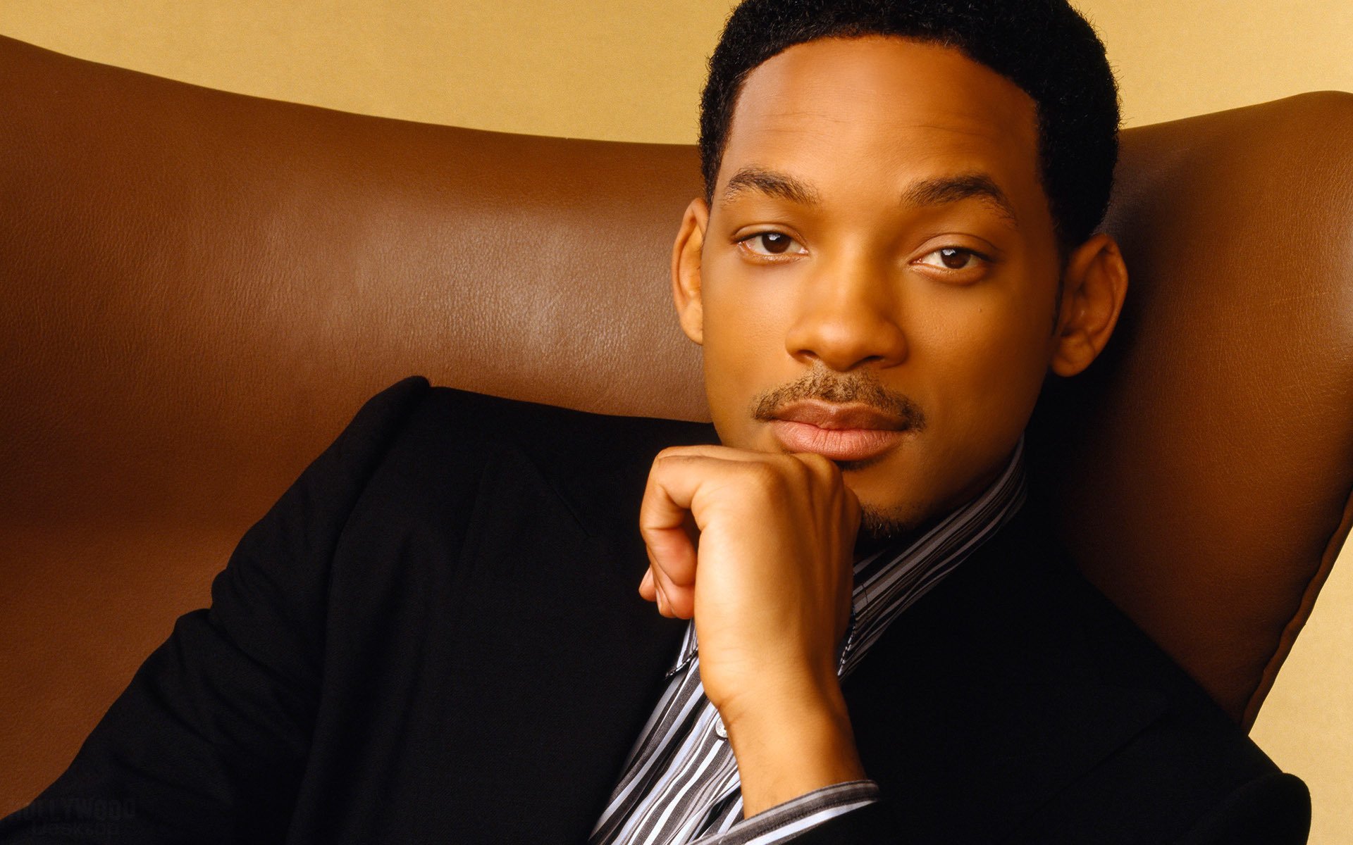 Actor Will Smith is sitting in a brown armchair