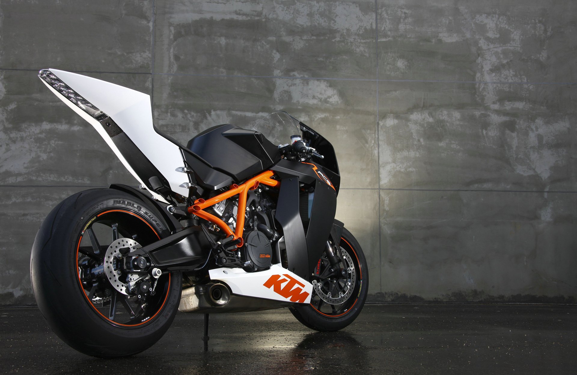 The ktm rc8 sports bike stands against a concrete wall