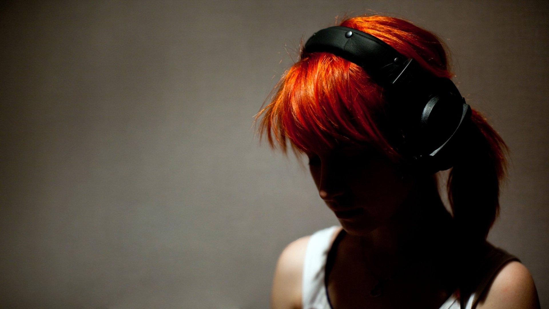 A girl with red hair wearing headphones
