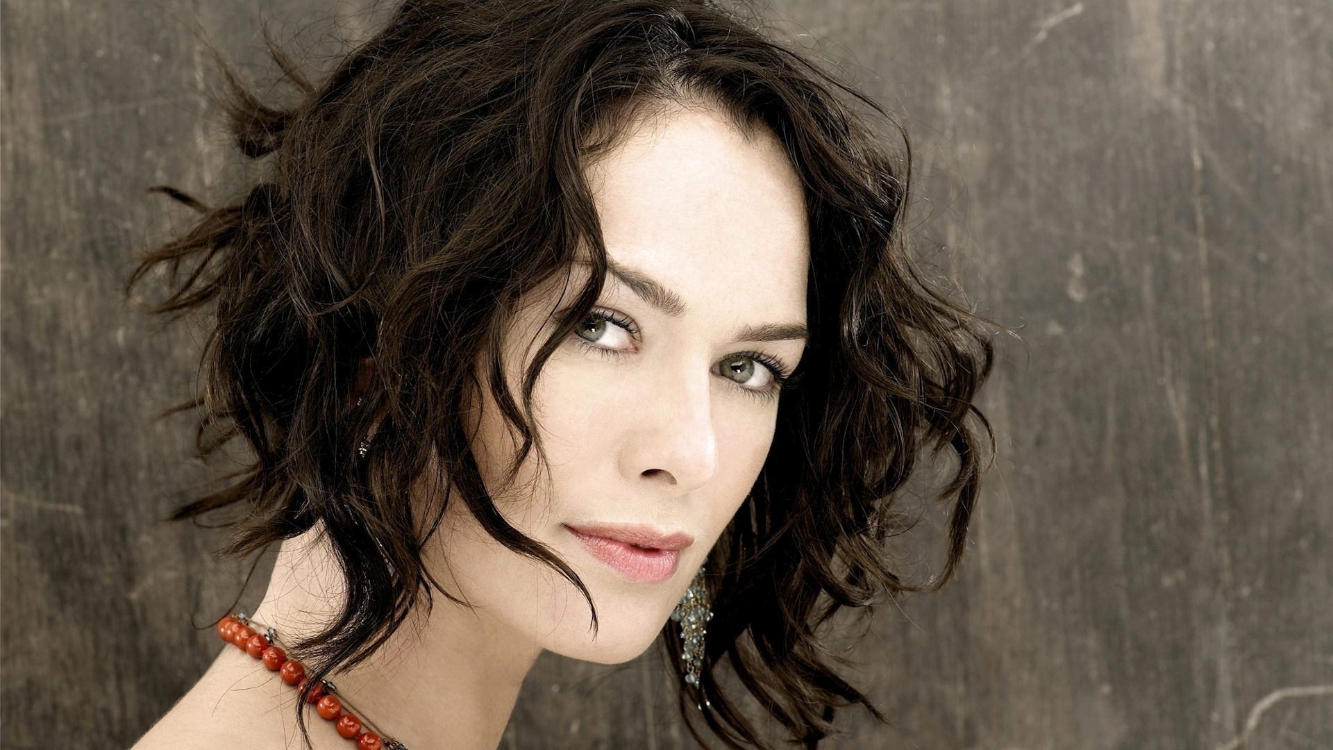Lena Headey with disheveled hair looks at the camera