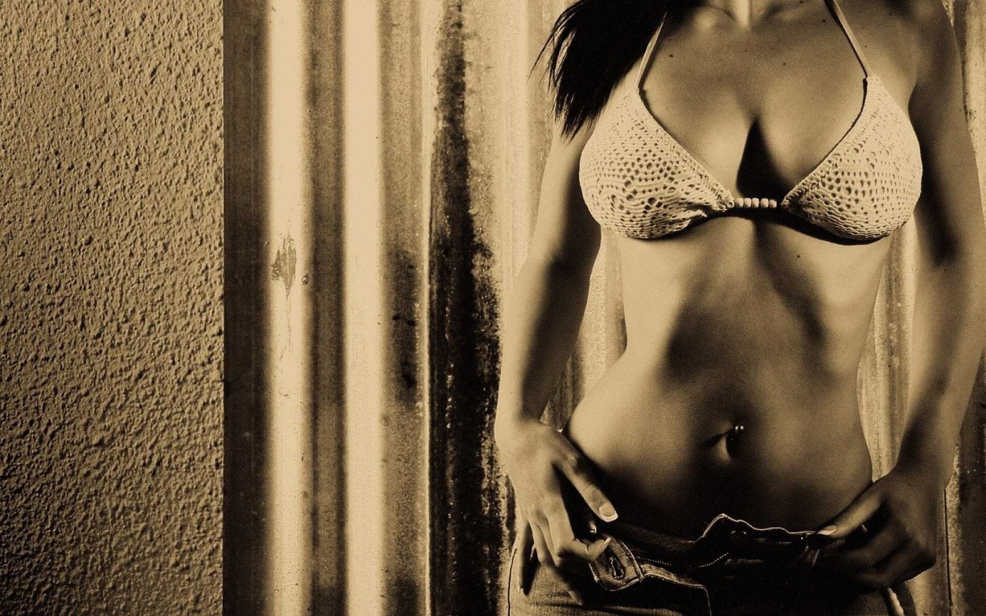 Erotic photo of a girl in jeans with a piercing on her stomach