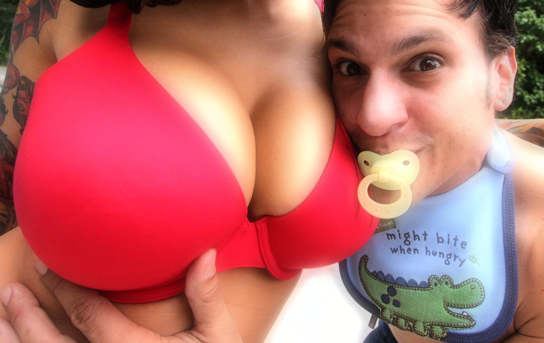 A girl with awesome breasts, to which a guy with a nipple in his mouth is pressed