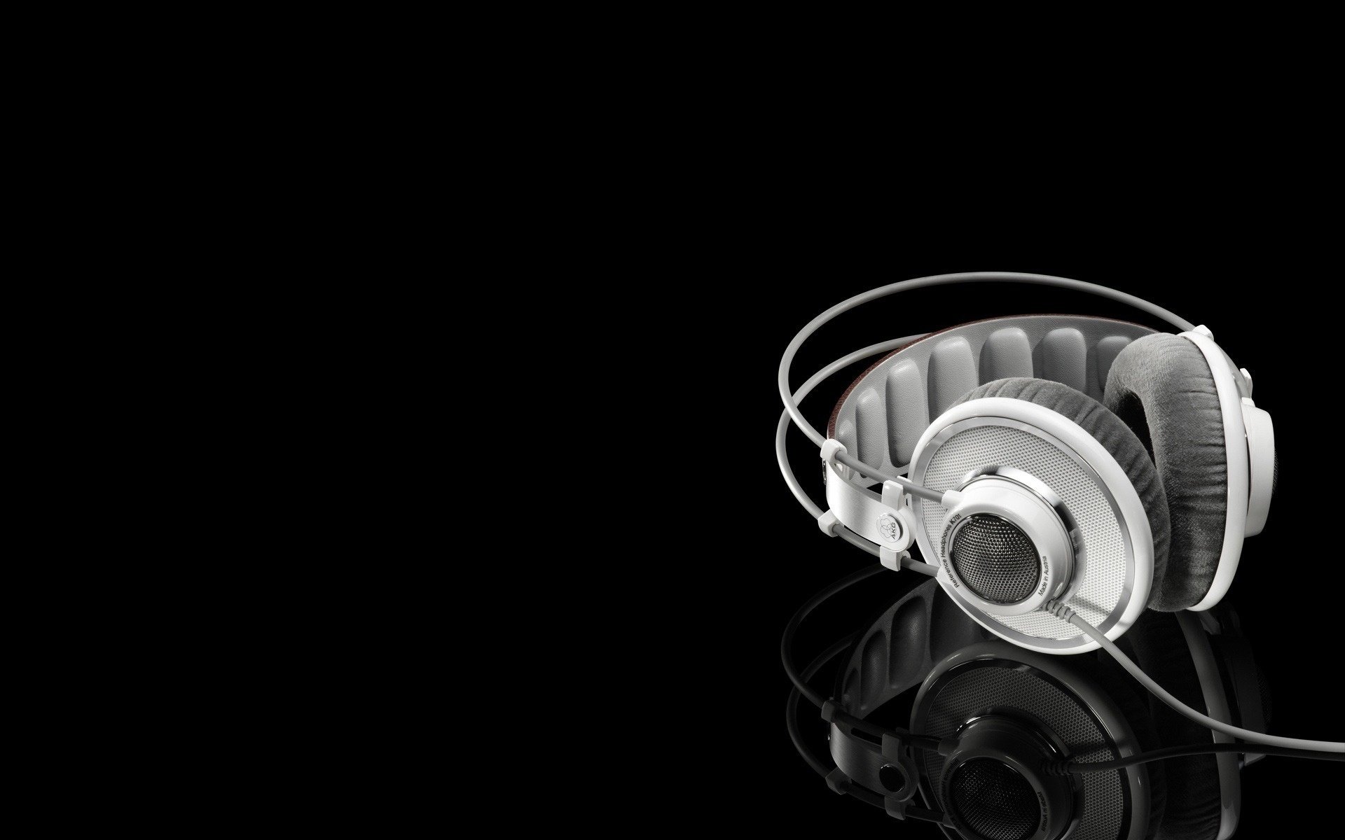 White headphones on a mirror surface and a black background