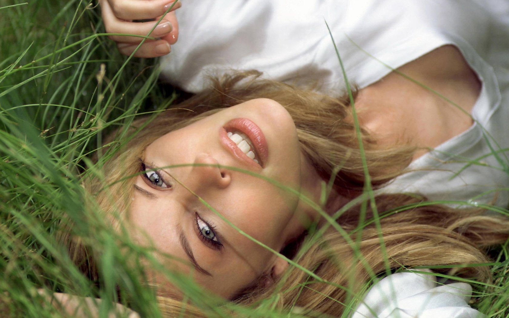 Blonde girl smiling sexy lying in the grass