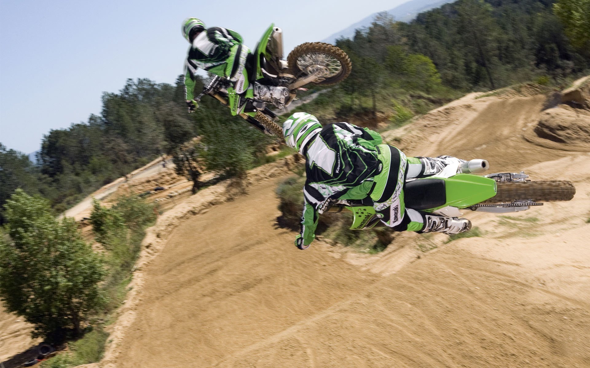 Sand track motocross bikers in flight