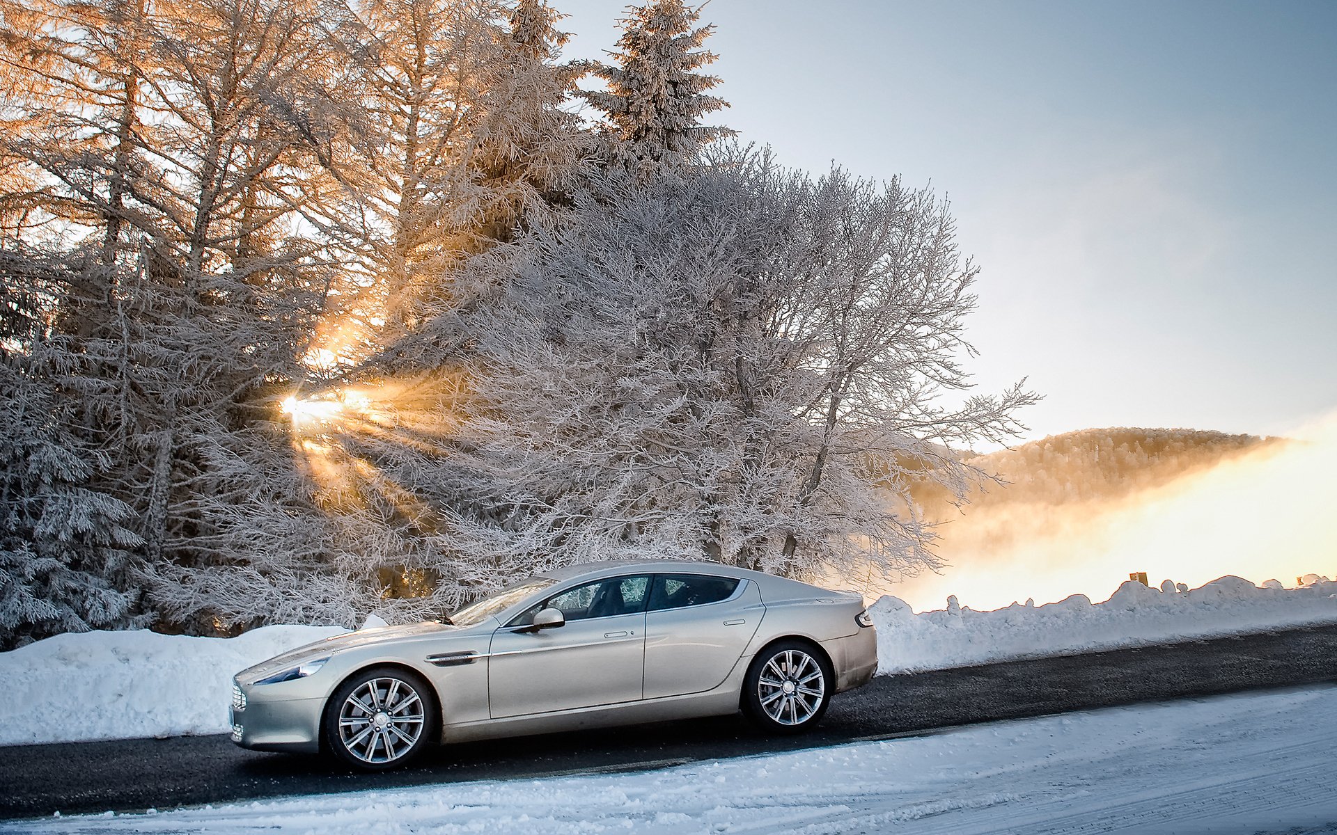 aston martin rapide rapid sedan a side view winter snow tree sky sun