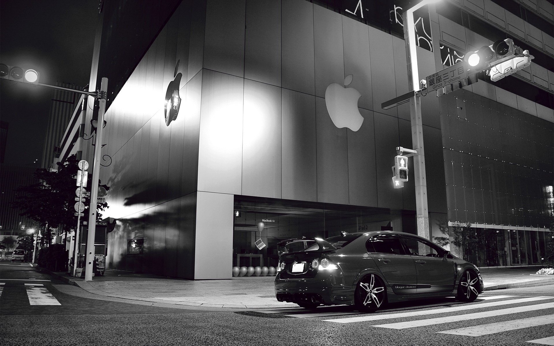 Black and white photo of a car near the apple building