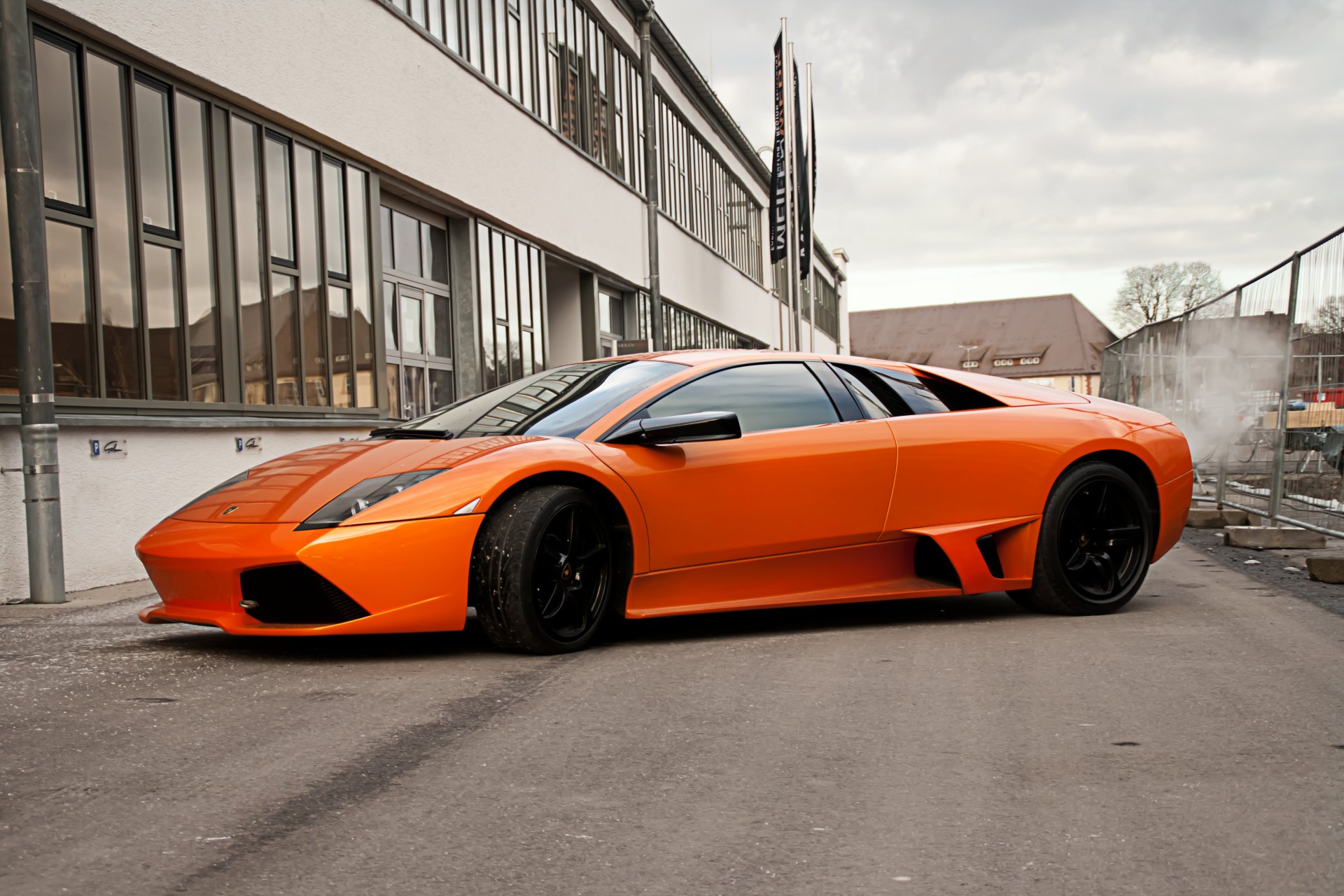 lamborghini murcielago orange lp640 murselago a side view black wheels building window fencing sky clouds