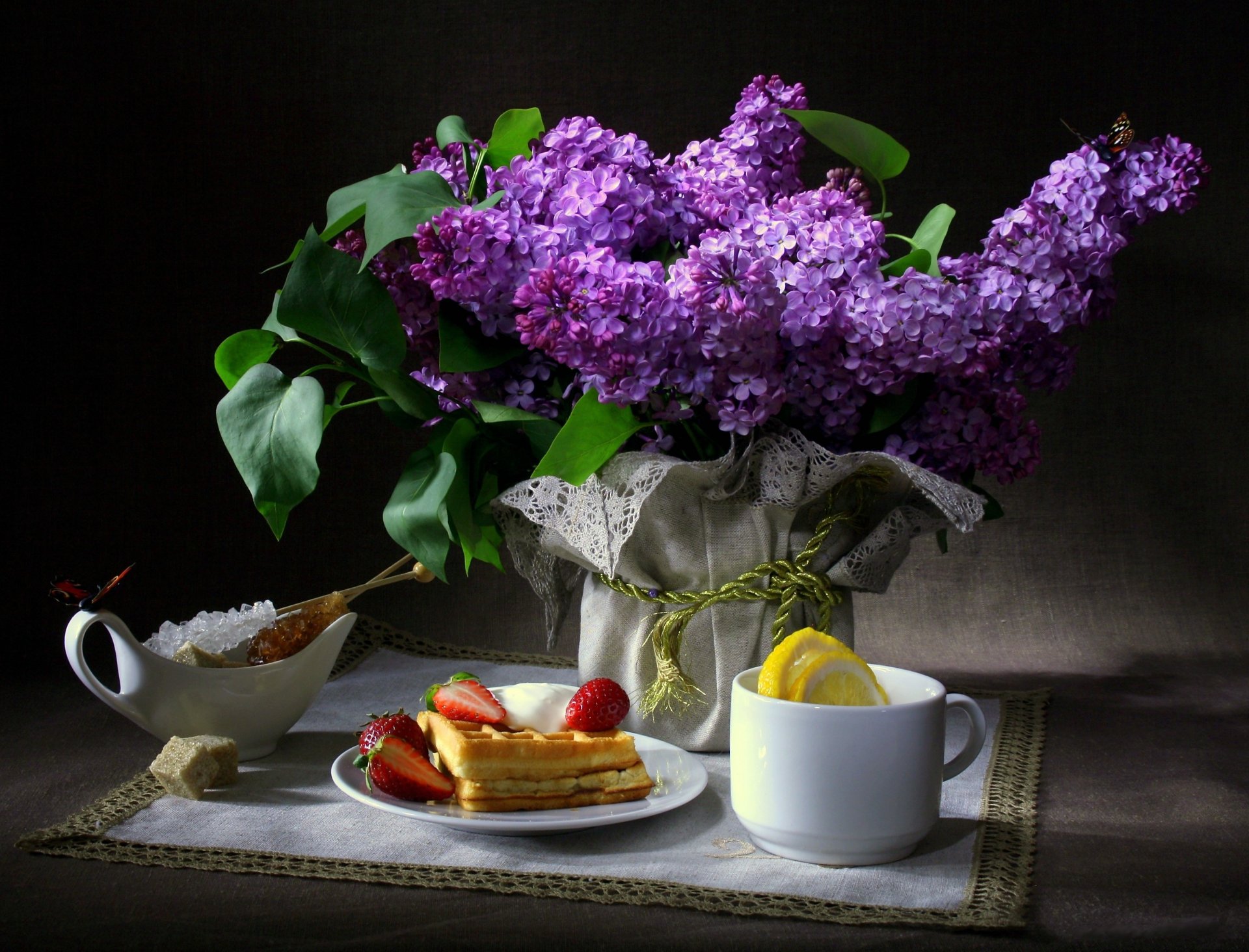 still life flower lilac butterfly breakfast wafer strawberry cup lemon sugar napkin dark background