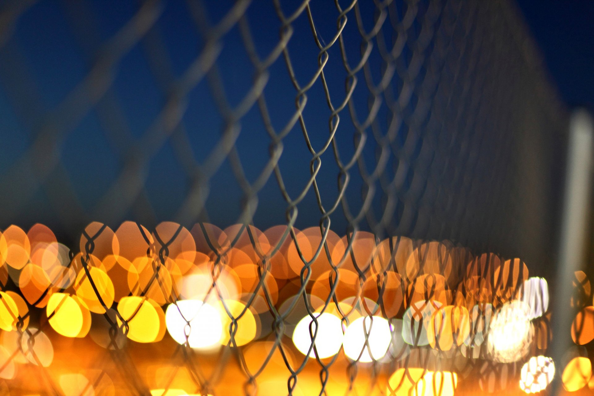 fence net metal close up lights yellow orange blur
