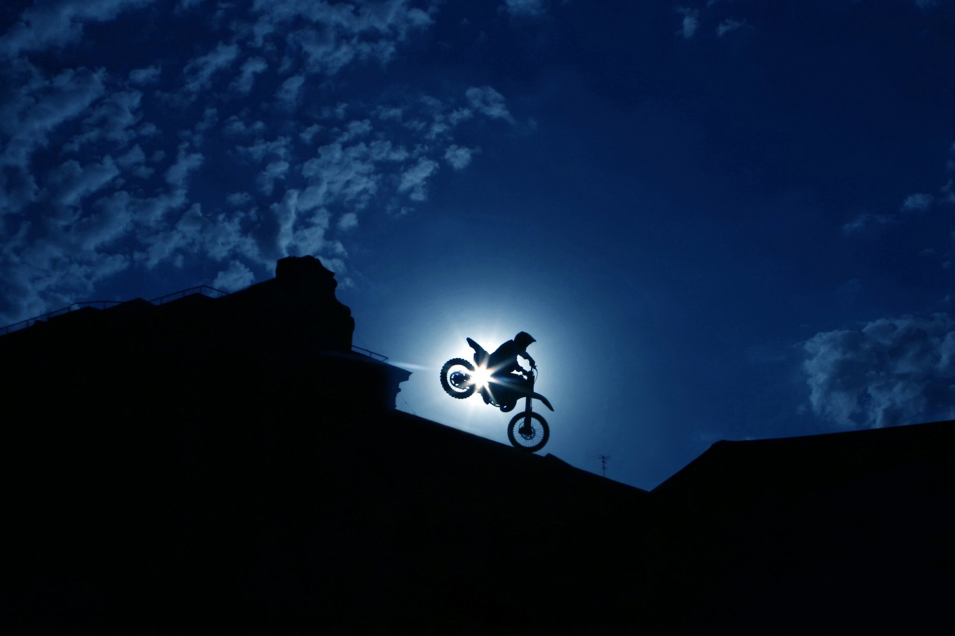 silhouette man rider racer transport extreme bike biker effective skilful maneuver stunt night town sky clouds beautiful background wallpaper.