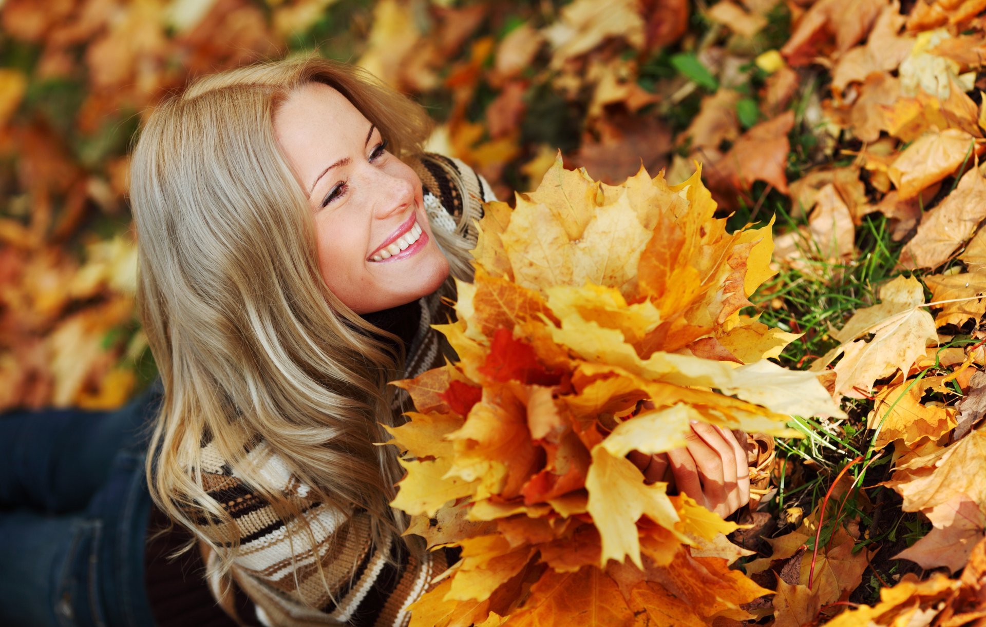 girl smile view blonde is jeans sweater autumn grass leaves