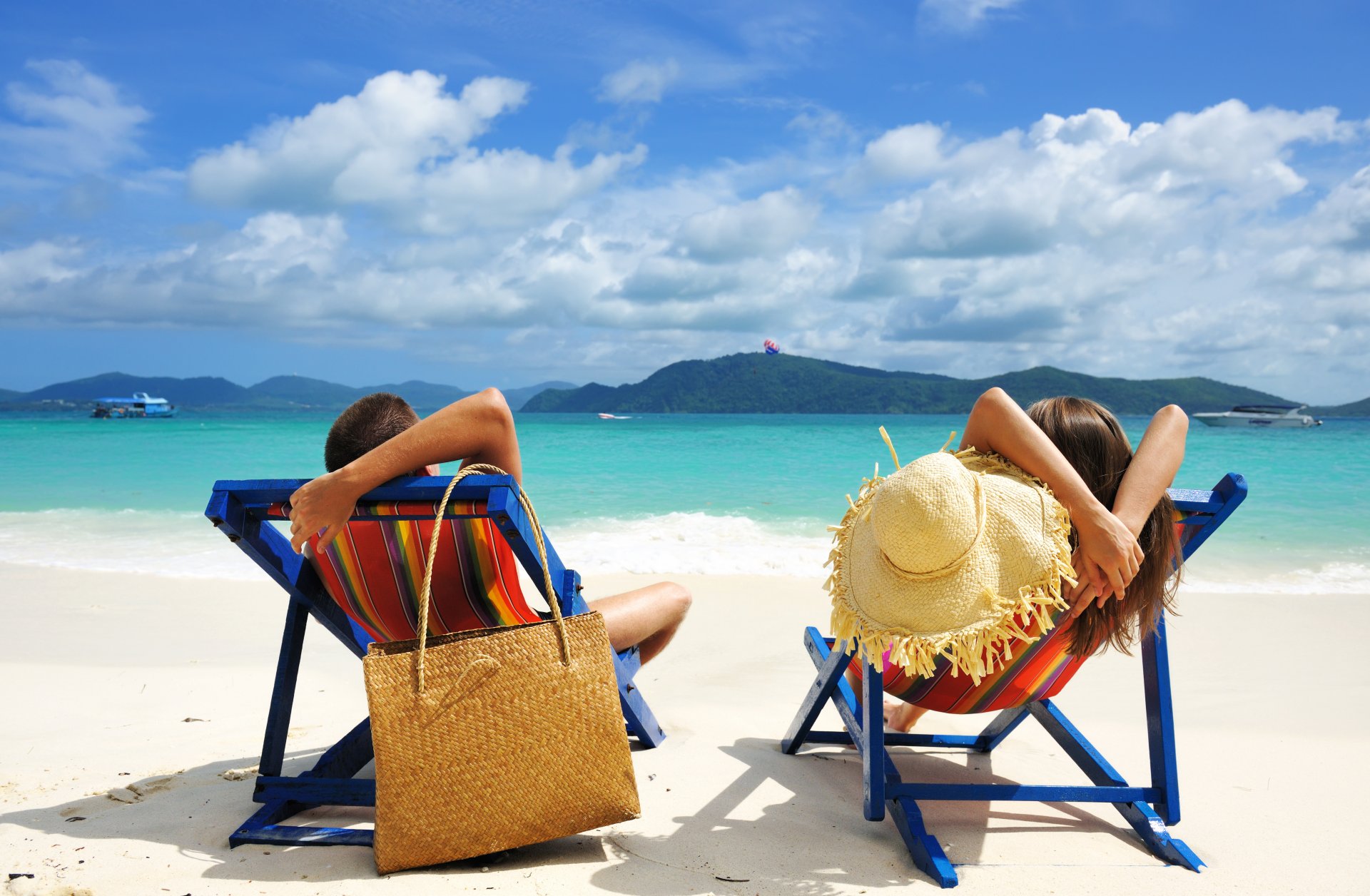 vacation relax couple man woman boy girl people beach sand sea water sky clouds islands beach chairs bag hat summer boats tropical landscape nature holiday