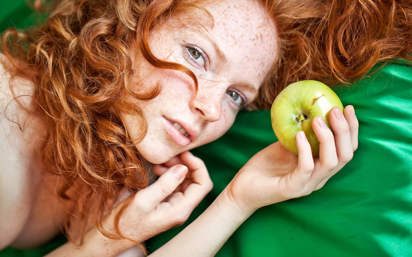 Red-haired model with an apple in the palm of her hand