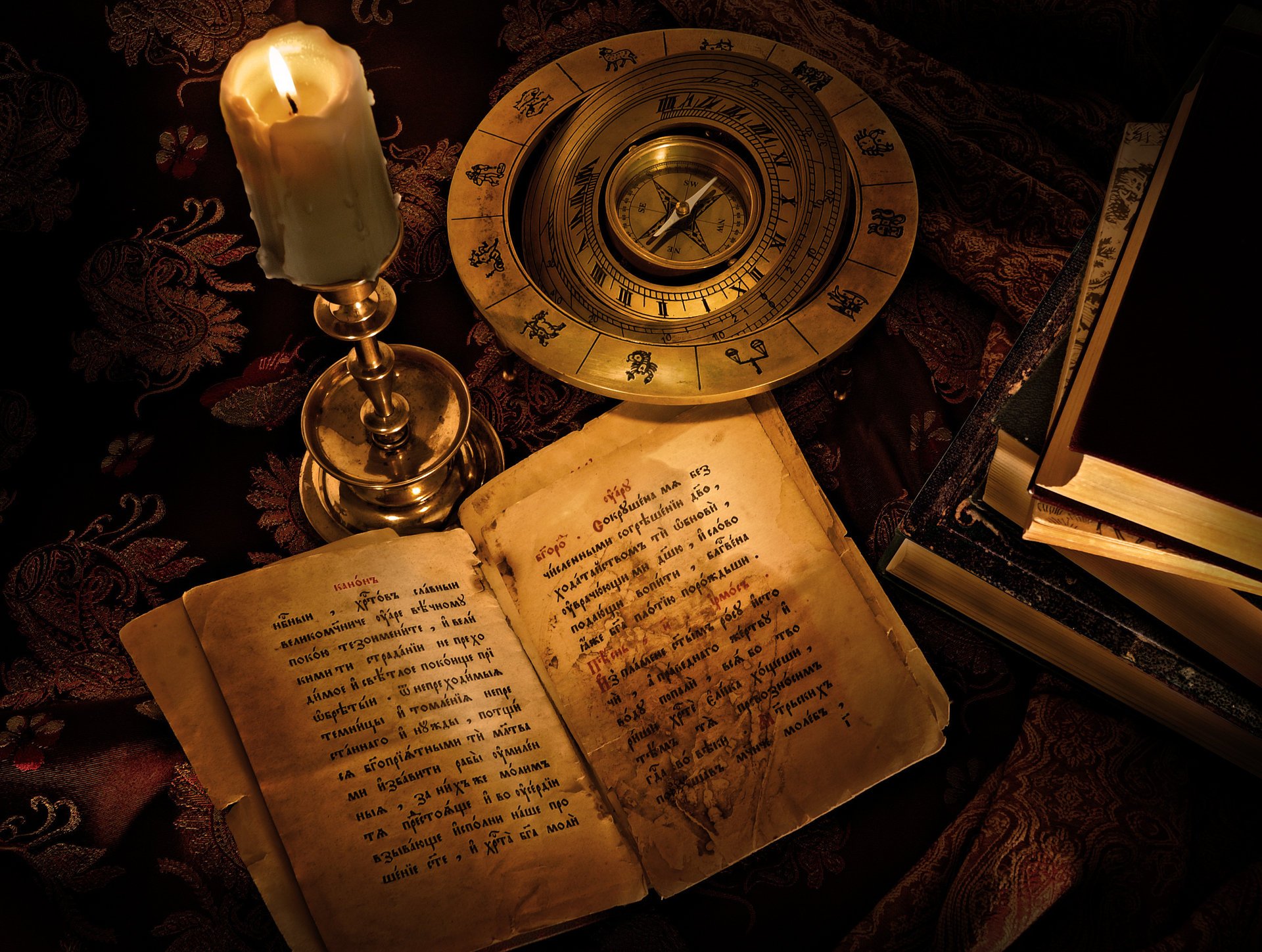 Zodiac signs. A candle on the table. An open book. Antique compass