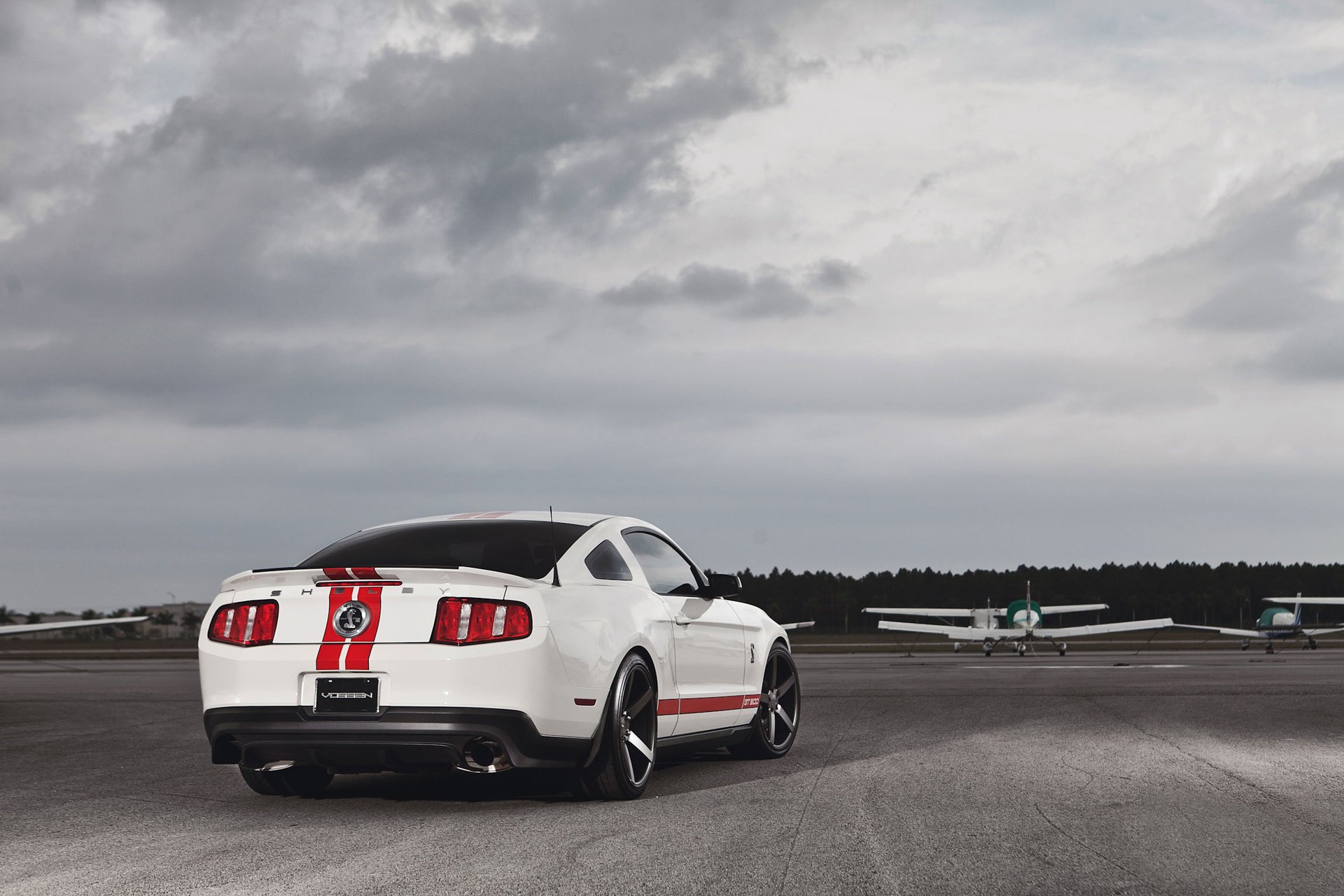White mustang at the aerodrome with airplanes