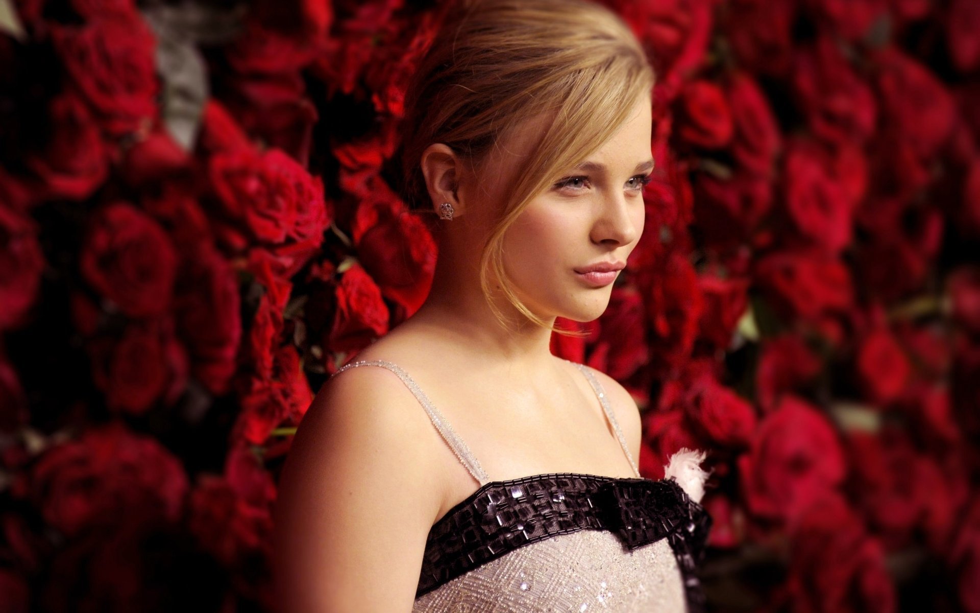 Chloe Grace Moretz against a wall of red roses