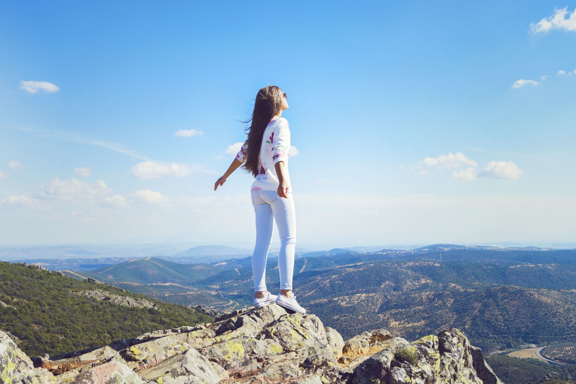 girl mountain jeans wind hair pose is horizon sky clouds