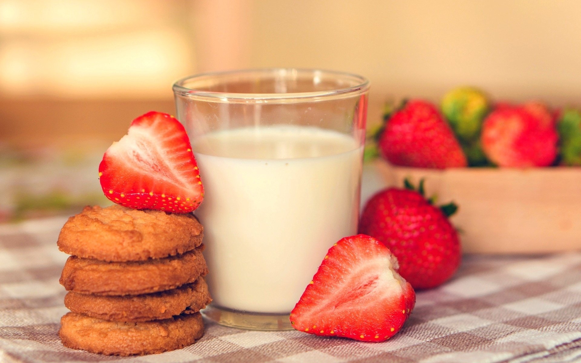 A glass of milk with strawberries and cookies