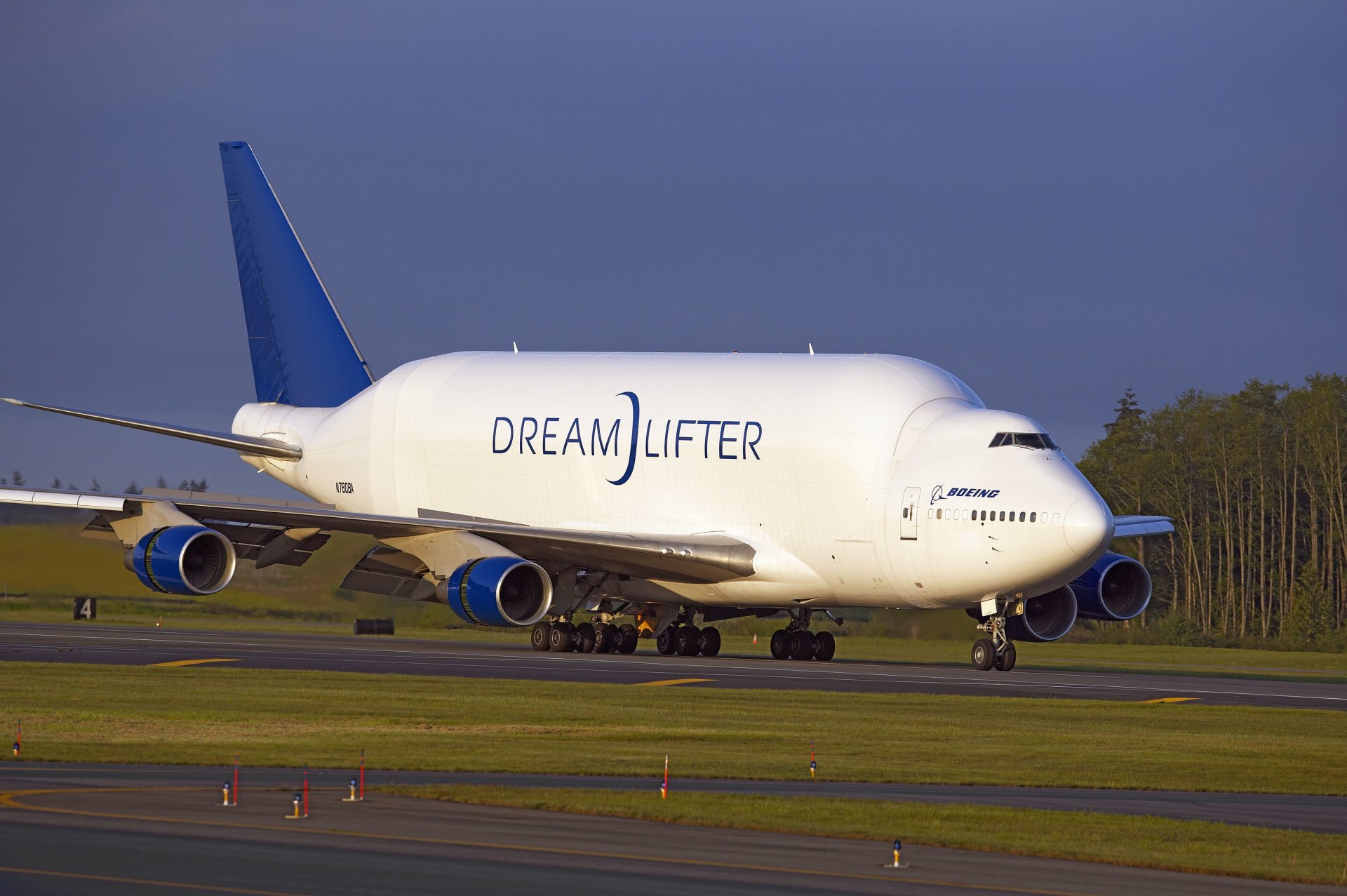 dreamlifter boeing plane trucks airport planting takeoff the band wings engines chassis tree sky aircraft cargo landing runway trees