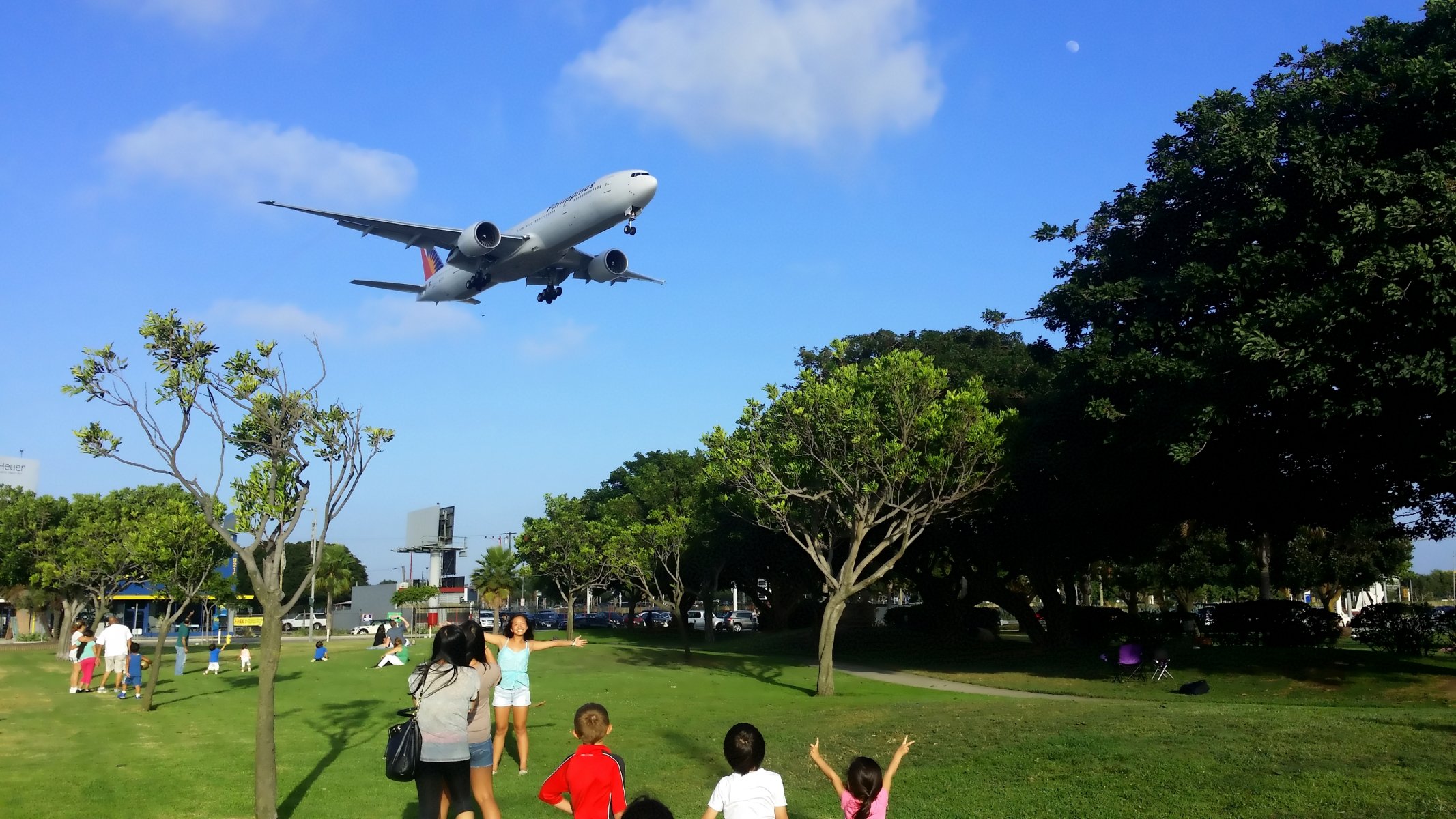 passenger airliner boeing er philippines airlines plane planting chassis sky clouds people park tree summer airplane landing trees