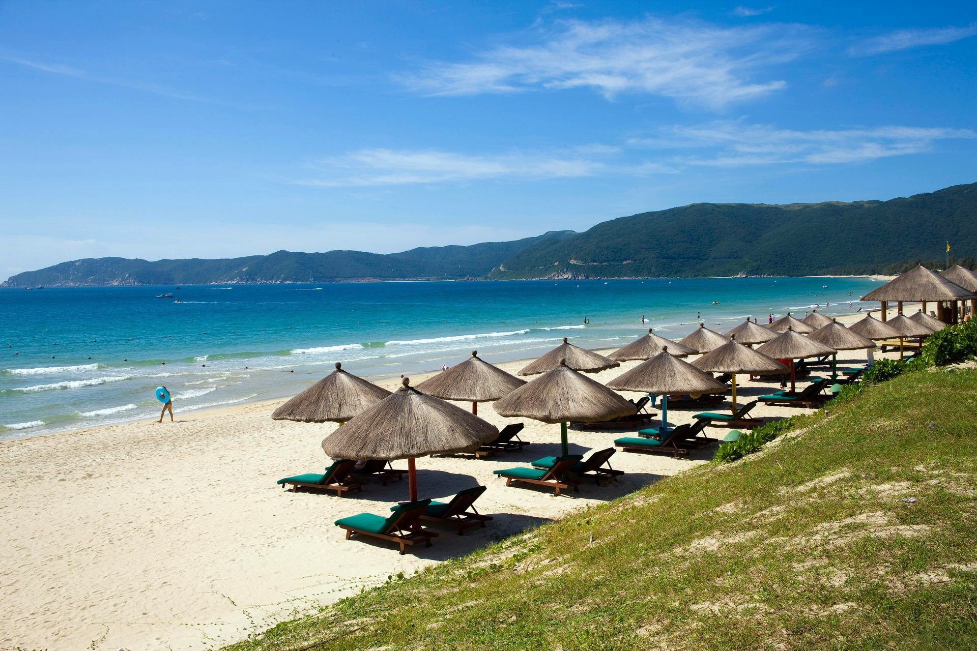 sea ocean coast beach sand umbrellas straw the distance sky mountain resort sports chairs waves