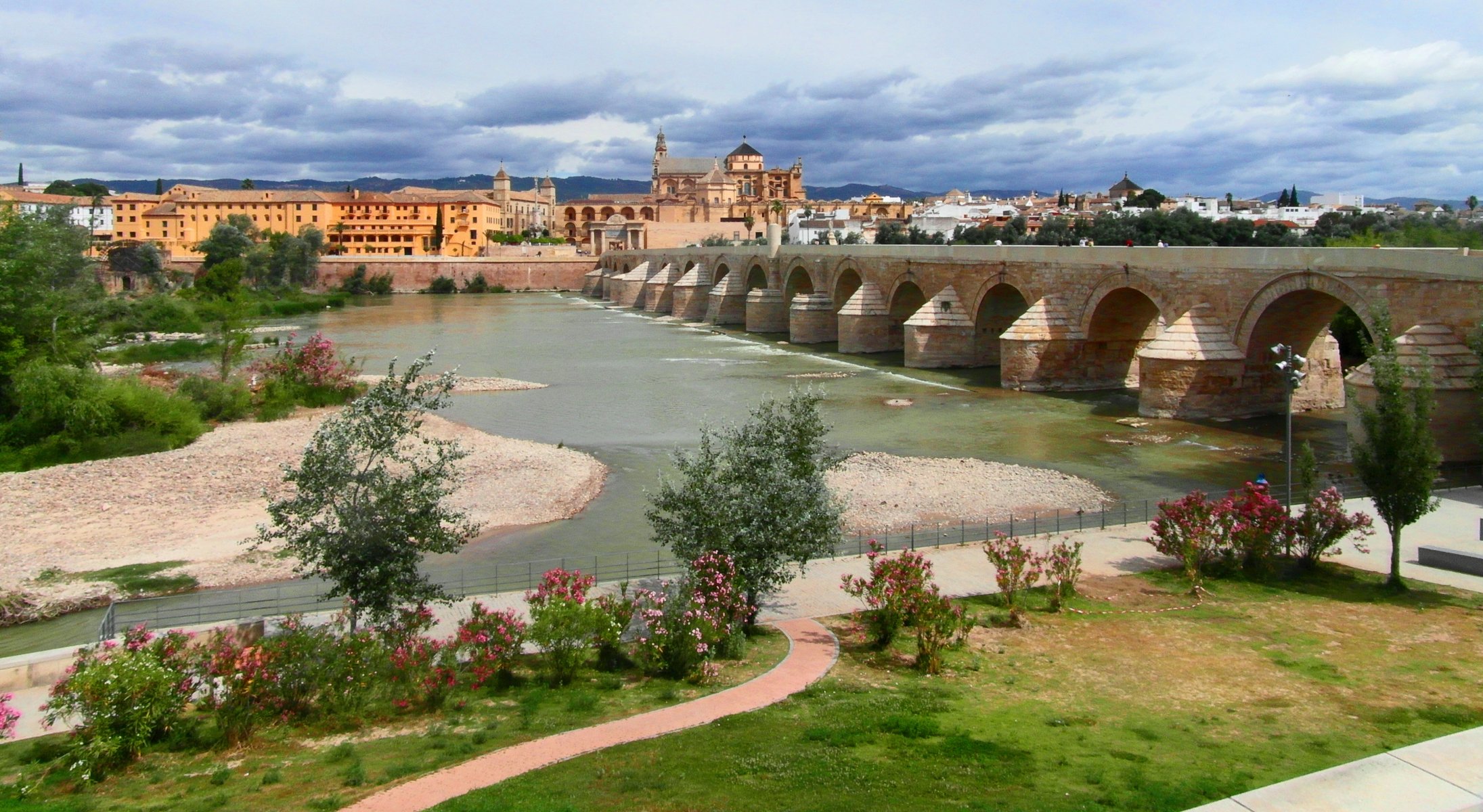 cordoba andalusia spain river guadalquivir 16- frame roman old bridge embankment tree bush flower