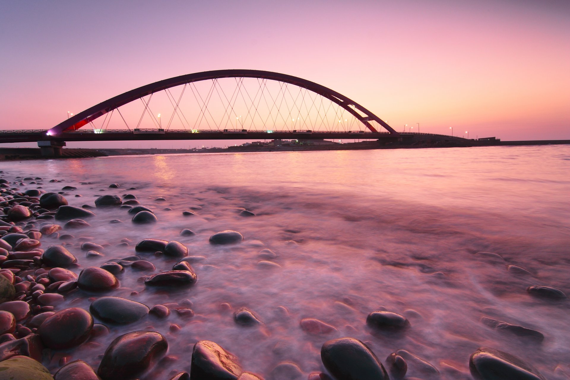 germany fehmarnsund bridge pink sunset night bridge lamps light sea ocean calm beach stones